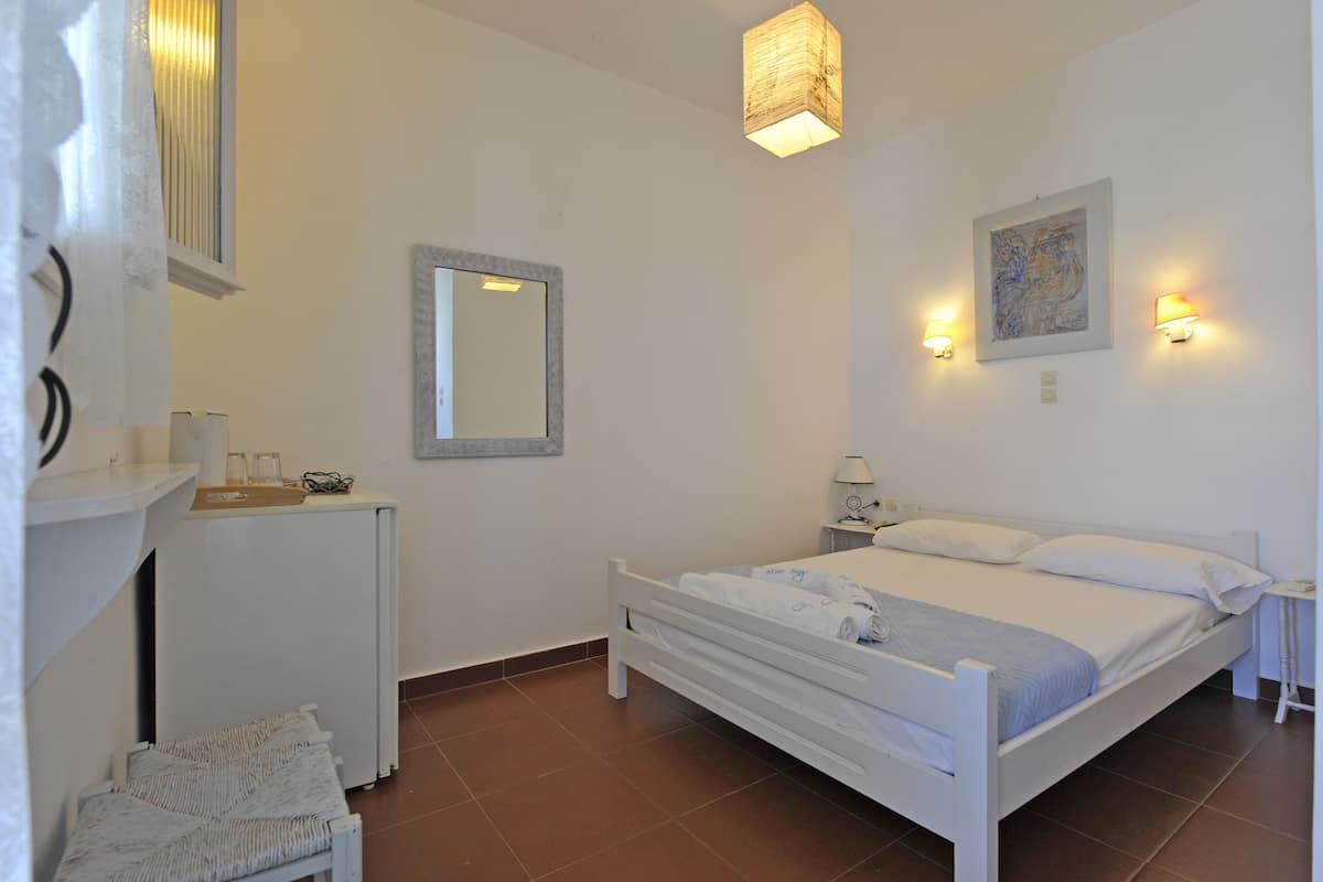 A bedroom with a bed, bedside tables, a mirror, and a hanging light fixture.