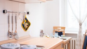 A kitchen with a wooden countertop, hanging utensils, a coffee maker, and a chair near a window. - Zimmervermietung Härtig (Berlin)