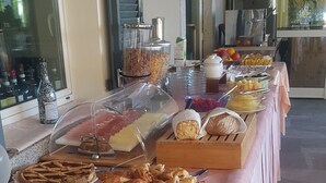 A buffet table with various food items and a jug of orange juice.
