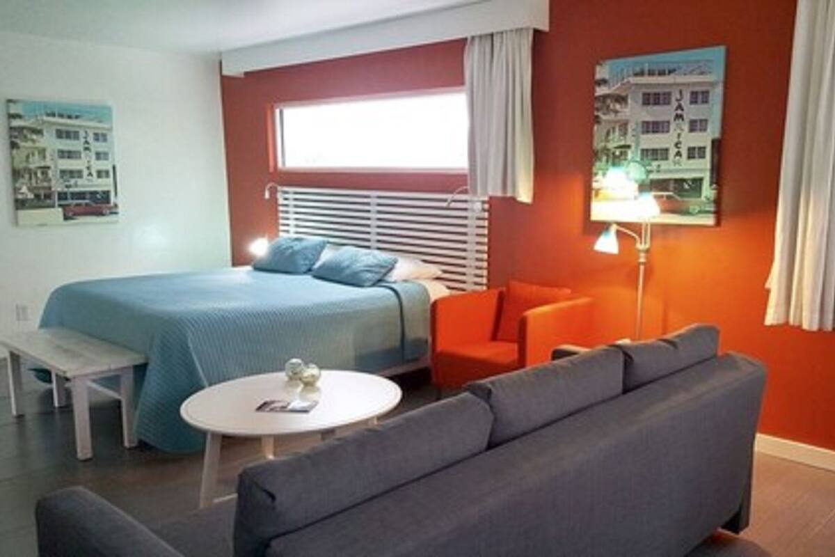 Una habitación de hotel con cama, sofá, una mesita y una lámpara.