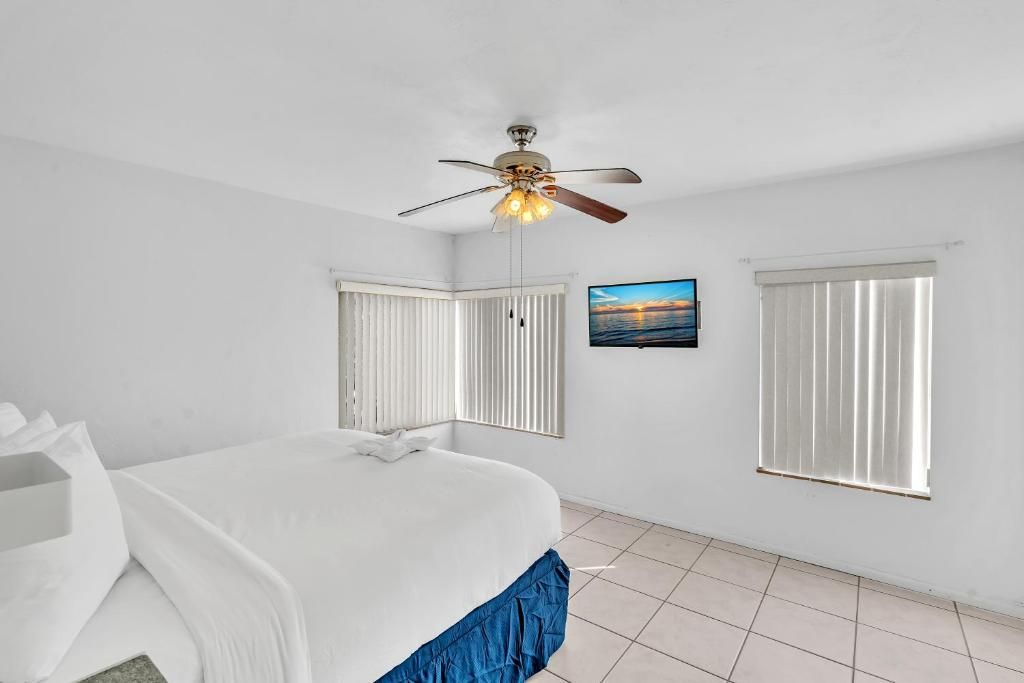 A bedroom with a bed, a ceiling fan, a window with blinds, and a picture on the wall.