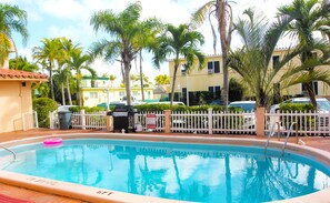 A swimming pool surrounded by palm trees and a white picket fence. - Hollywood Beach Swan (Hollywood)