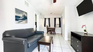A living room with a sofa, coffee table, TV, and artwork.
