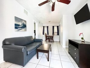 A living room with a sofa, coffee table, TV, and artwork. - Hollywood Beach Swan (Hollywood)