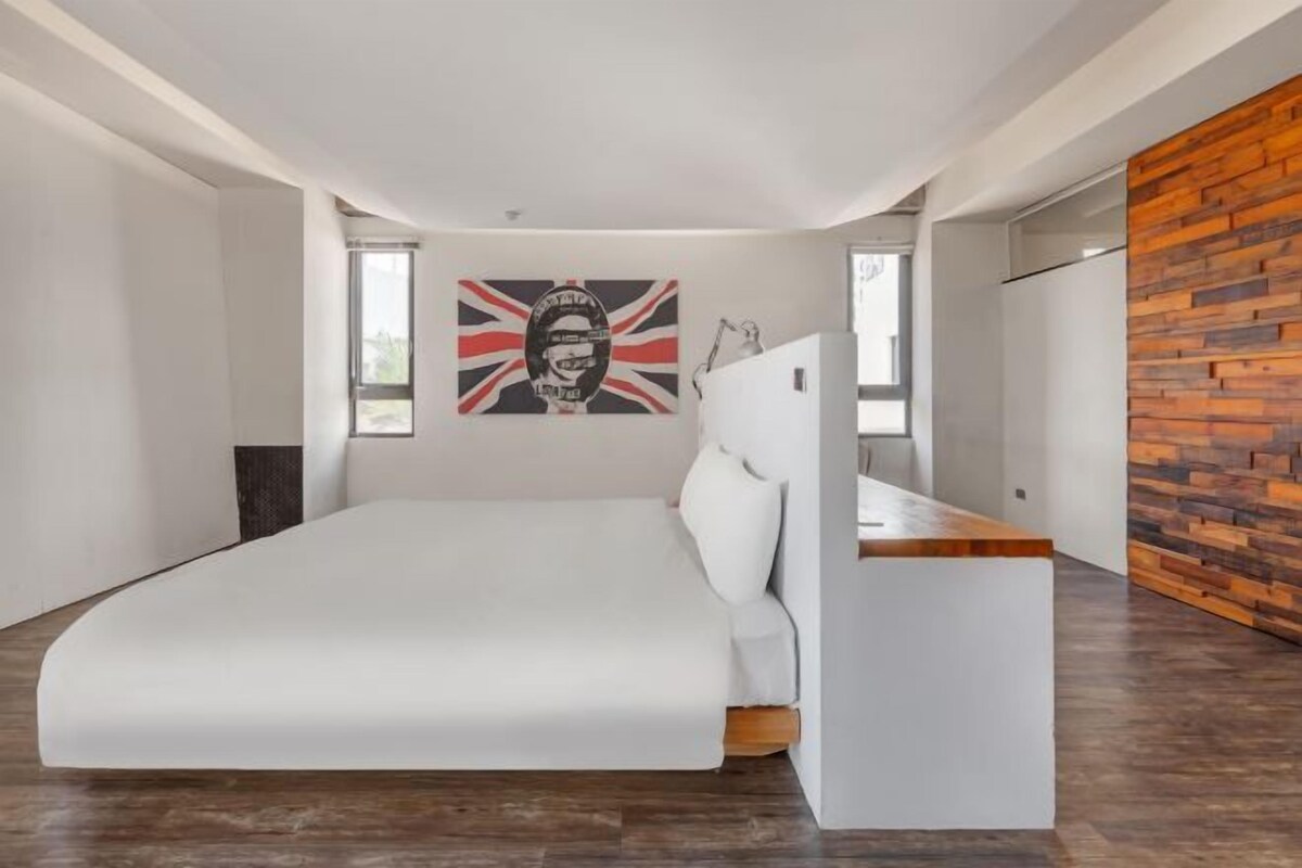 Un dormitorio moderno con una cama grande, un panel de madera decorativo y una obra de arte colgada en la pared.