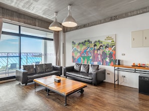 A modern living room with a sofa, coffee table, and a large window with a view. - El Puerto Hotel (Hengchun)