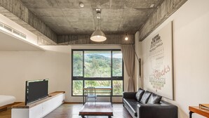 Una sala de estar moderna con un ventanal grande, un sofá, un televisor y una mesa.