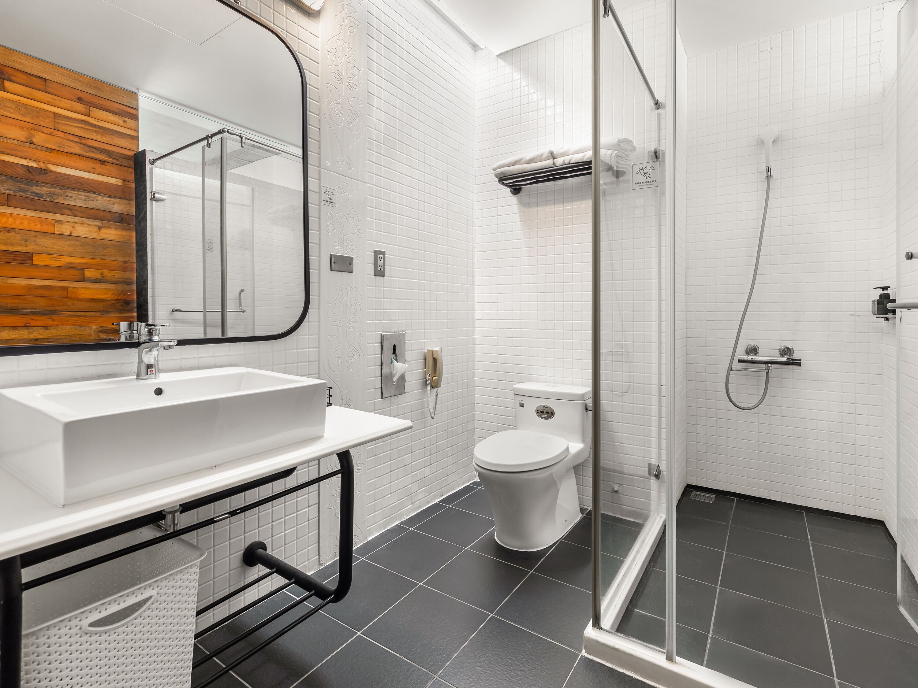A modern bathroom with a white sink, toilet, and glass shower enclosure.