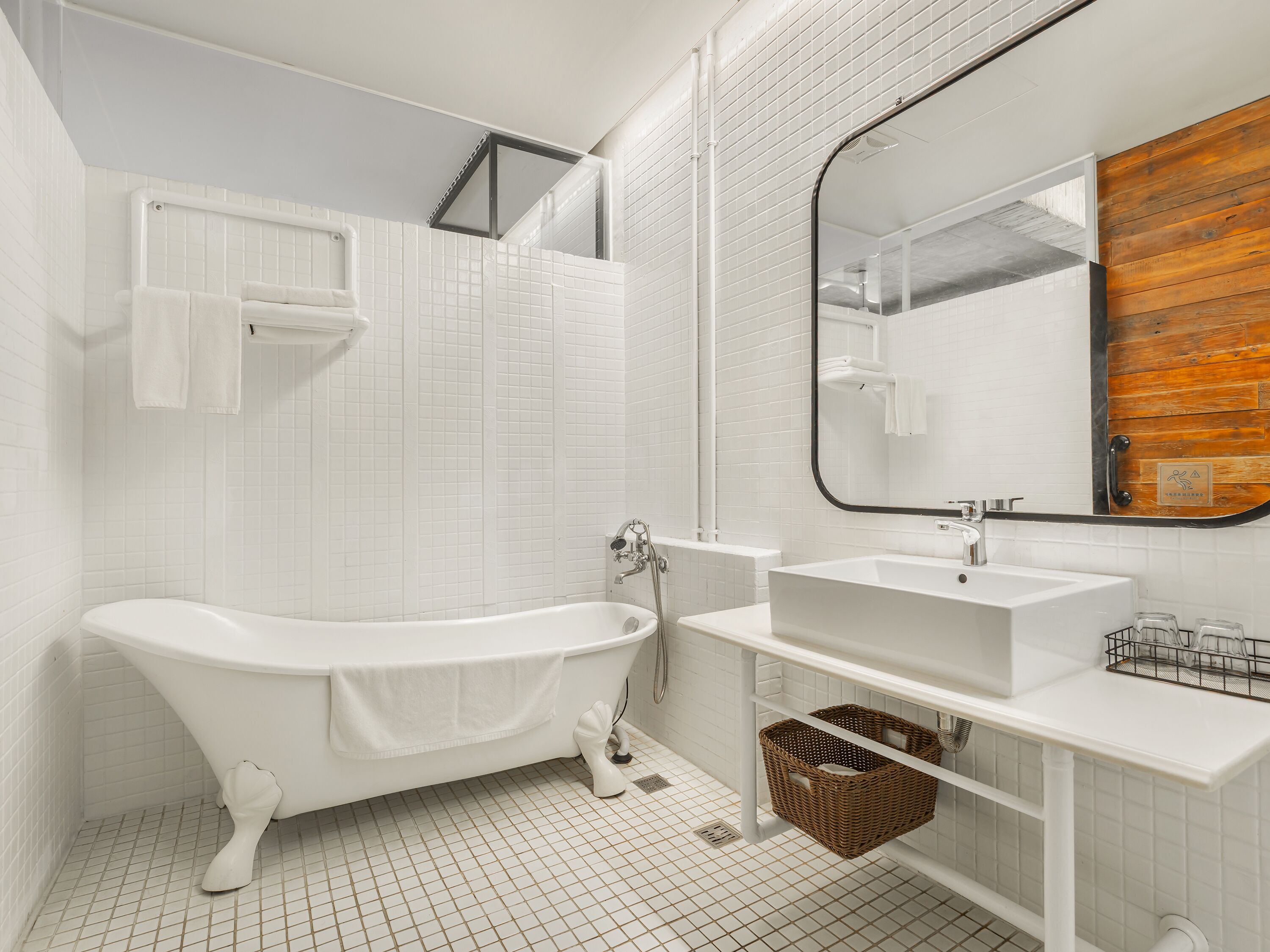 A modern bathroom with a freestanding bathtub, a large mirror, and a white sink.
