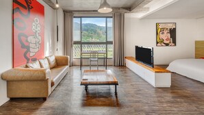 Una habitación moderna con sofá, mesa de centro, televisor y un ventanal con vistas a zonas verdes.