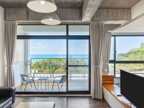 A modern room with a large sliding glass door leading to a balcony with a view of the ocean. - El Puerto Hotel (Hengchun)