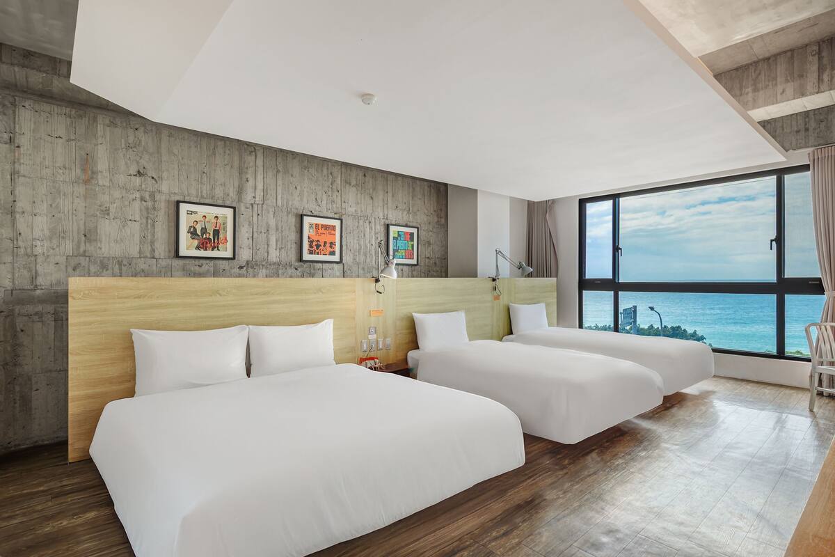 A hotel room with two beds, a large window with a view, wooden walls, and framed pictures.