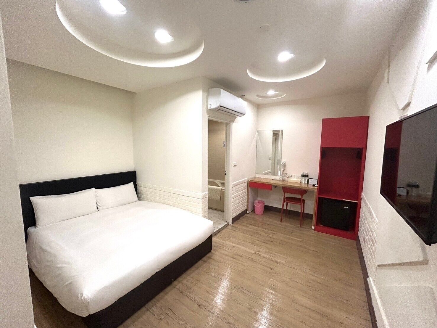 Een hotelkamer met een bed, een bureau, een spiegel en een televisie.
