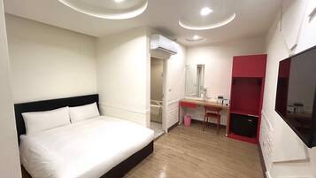 Een hotelkamer met een bed, een bureau, een spiegel en een televisie.