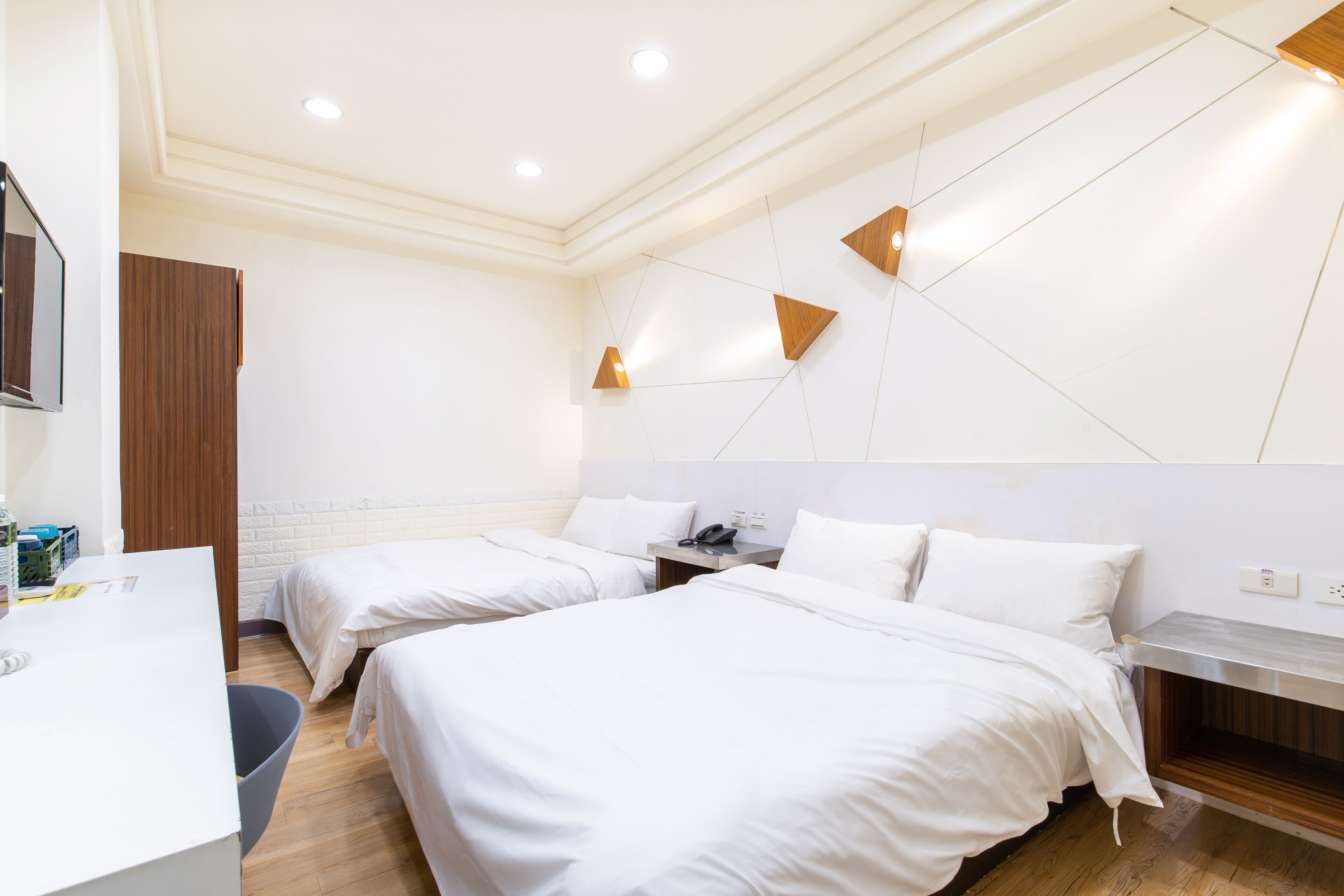 A hotel room with two beds, a desk, and a small seating area.