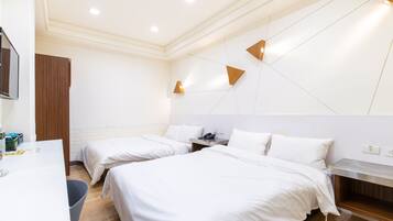 A hotel room with two beds, a desk, and a small seating area.