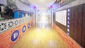 A corridor with a wooden floor, brick walls, and decorative panels. Signs indicate room numbers and directions. - Giant Rich King Plaza Hotel (Taipei)