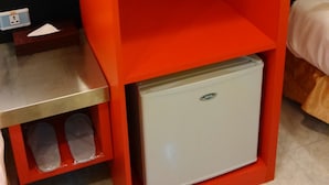 A red storage unit with a small refrigerator, a hanging rack, and a table with a power outlet. - Giant Rich King Plaza Hotel (Taipei)
