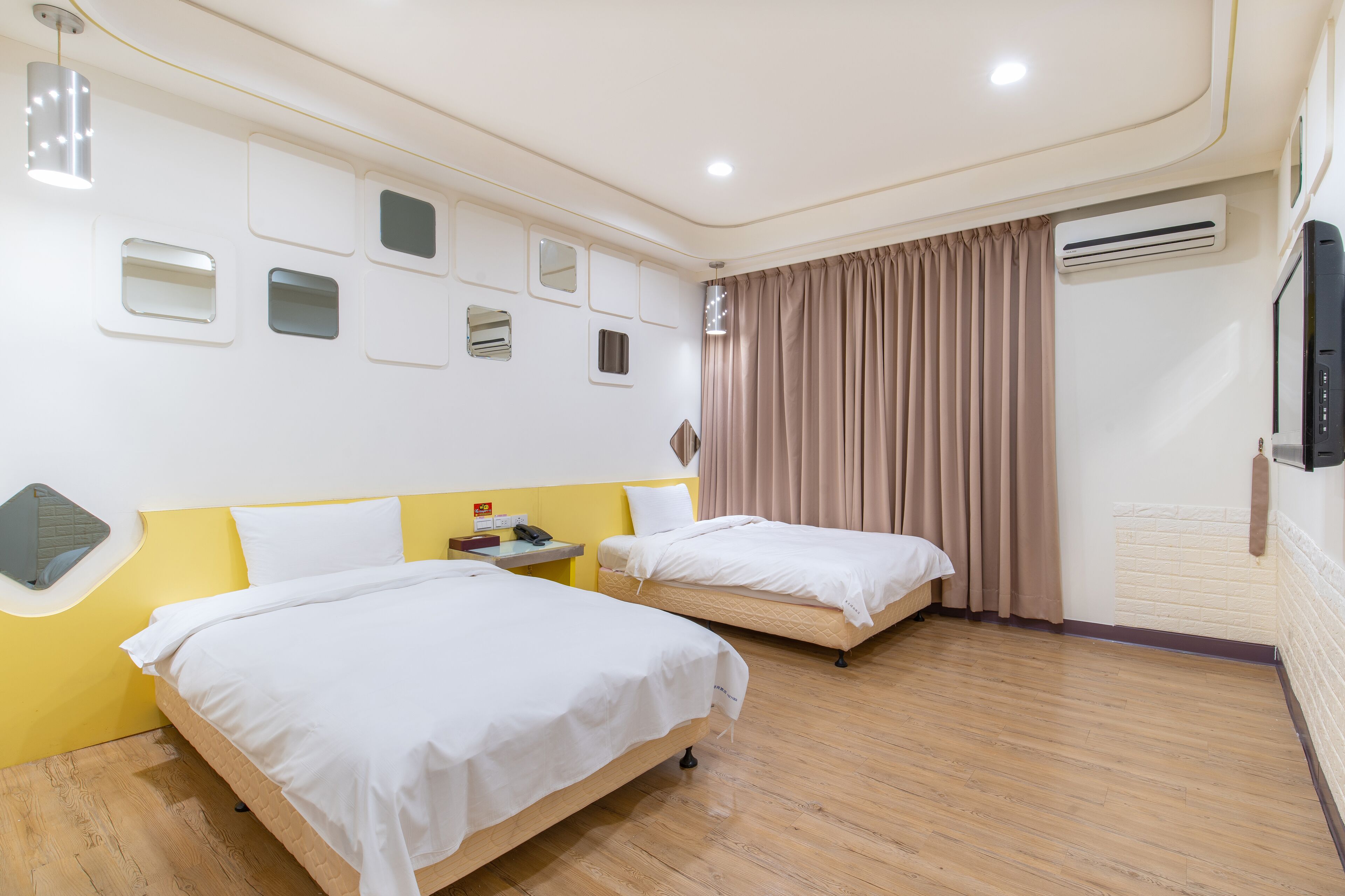 Een hotelkamer met twee bedden, een spiegel, een telefoon en een airconditioning.