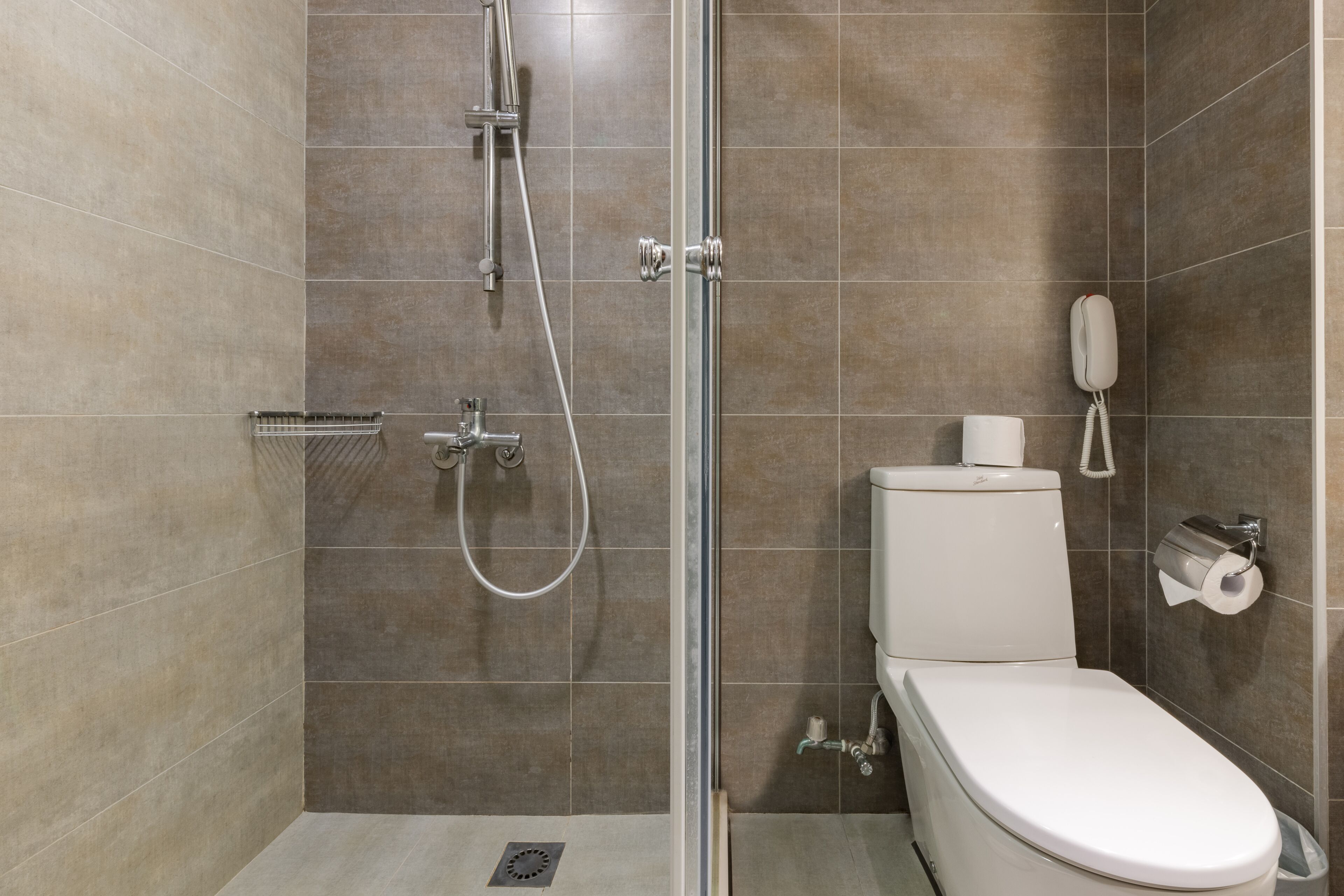 A modern bathroom with a shower, toilet, and a telephone.
