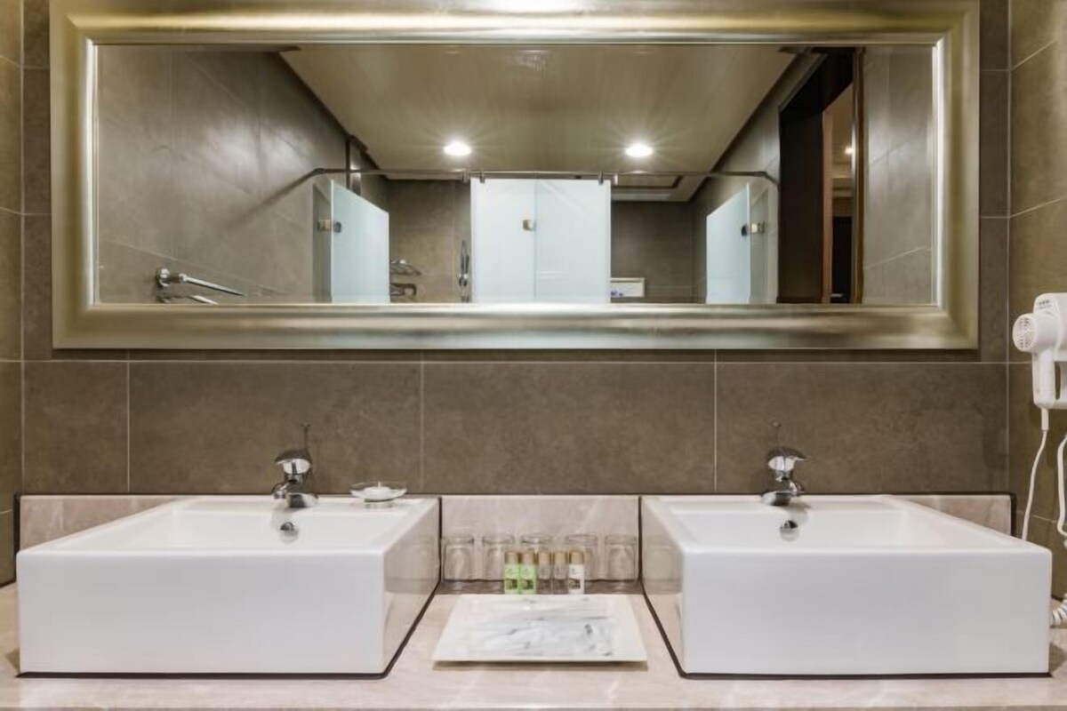 A bathroom with two sinks, a large mirror, and a towel rack.