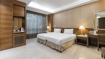 A hotel room with a large bed, a desk with a lamp, a wardrobe, and a mirror.