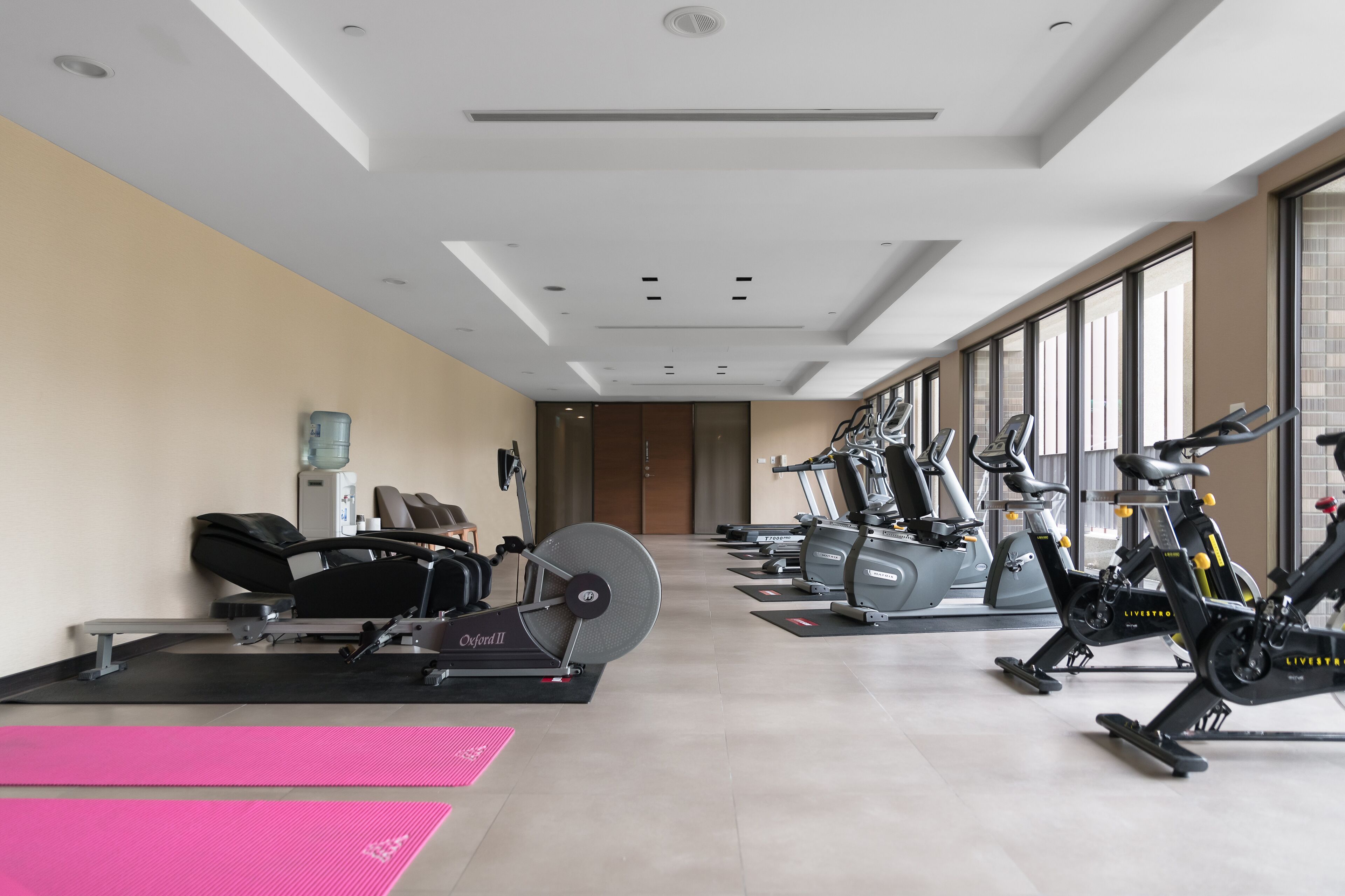 A gym with cardio machines, weight benches, and exercise mats.