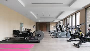 A gym with cardio machines, weight benches, and exercise mats.