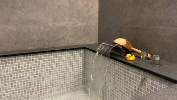 Un baño moderno con una bañera rectangular, un patito de madera como adorno, y un patito de goma amarillo.