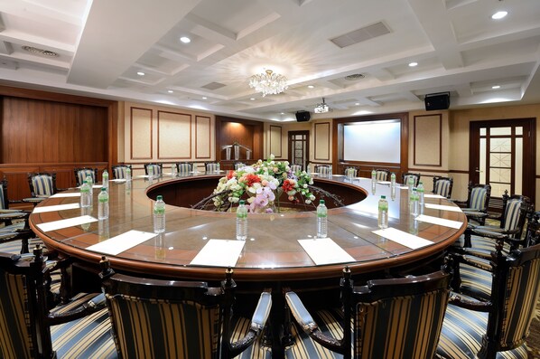 A conference room with a round table, chairs, floral centerpiece, and water bottles. - The Chitou Lemidi Hotel (Lugu)