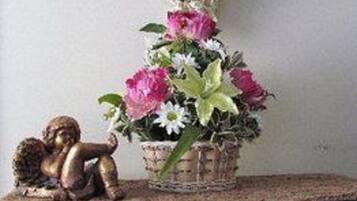 A decorative angel head on a wall, a small statue, and a basket of flowers on a dresser.