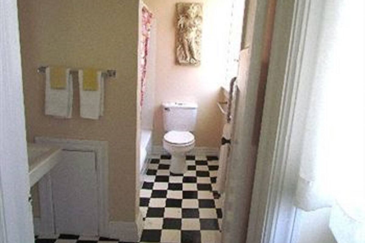 Un baño con piso a cuadros, un inodoro y un perchero para toallas.