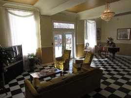 Un suelo de cuadros, un sofá, una silla, una mesa y una araña.