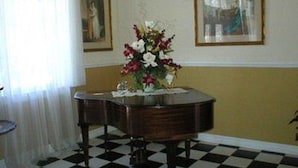 A room with a checkered floor, a round table with a vase of flowers, and two framed pictures on the wall.