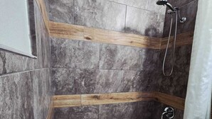 A bathroom with a bathtub, shower, and wooden accents on the walls.