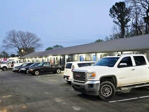 A parking lot with several GMC vehicles, a building with a flat roof, and trees in the background.