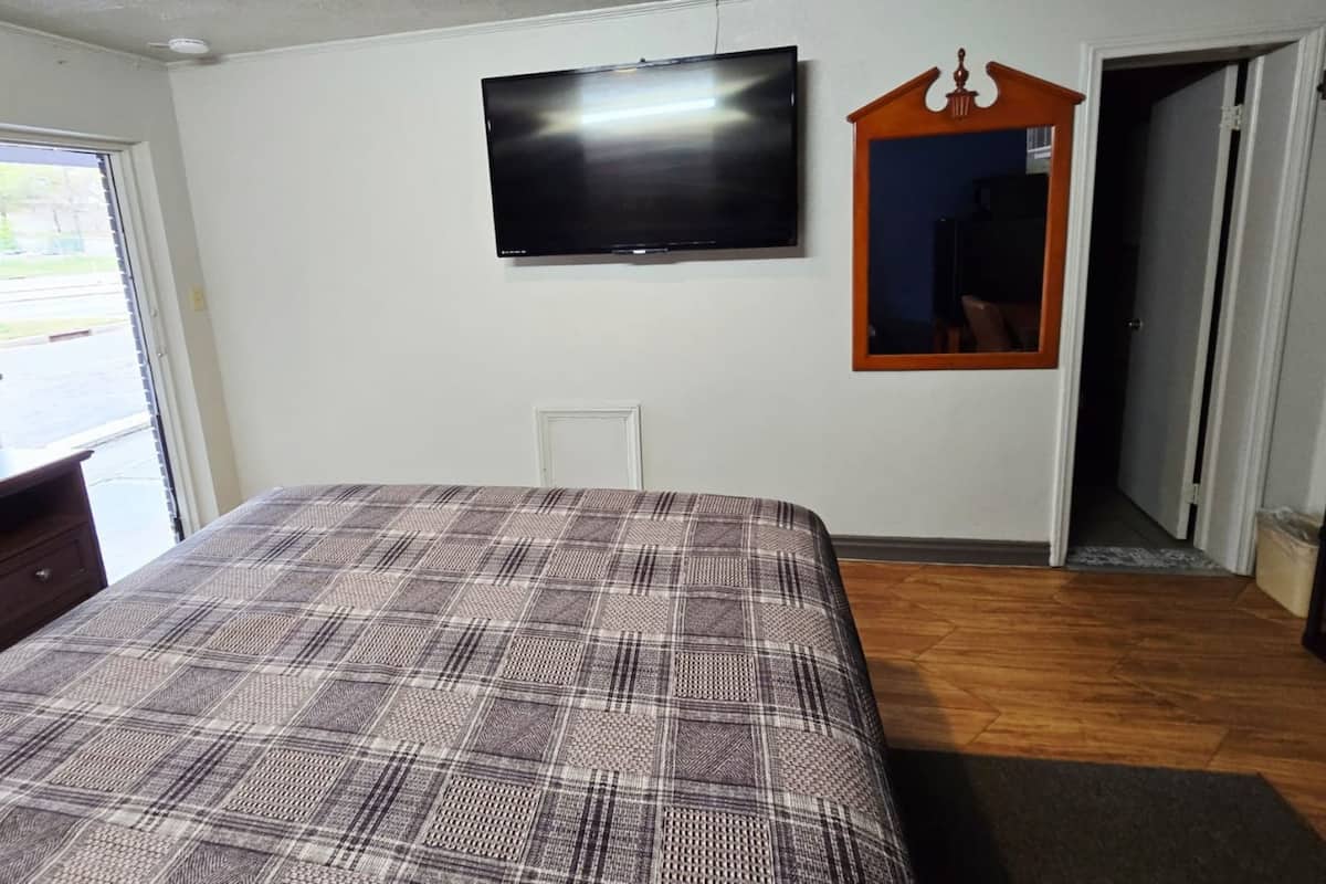 A bedroom with a bed, a television, a mirror, and a door.