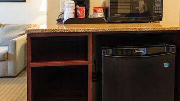 A compact kitchenette with a microwave, coffee maker, and a refrigerator.
