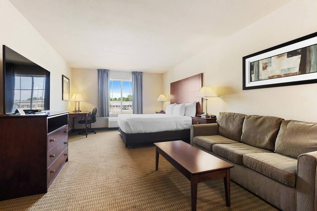 Une chambre d’hôtel avec un lit, un canapé, un bureau et une télévision.