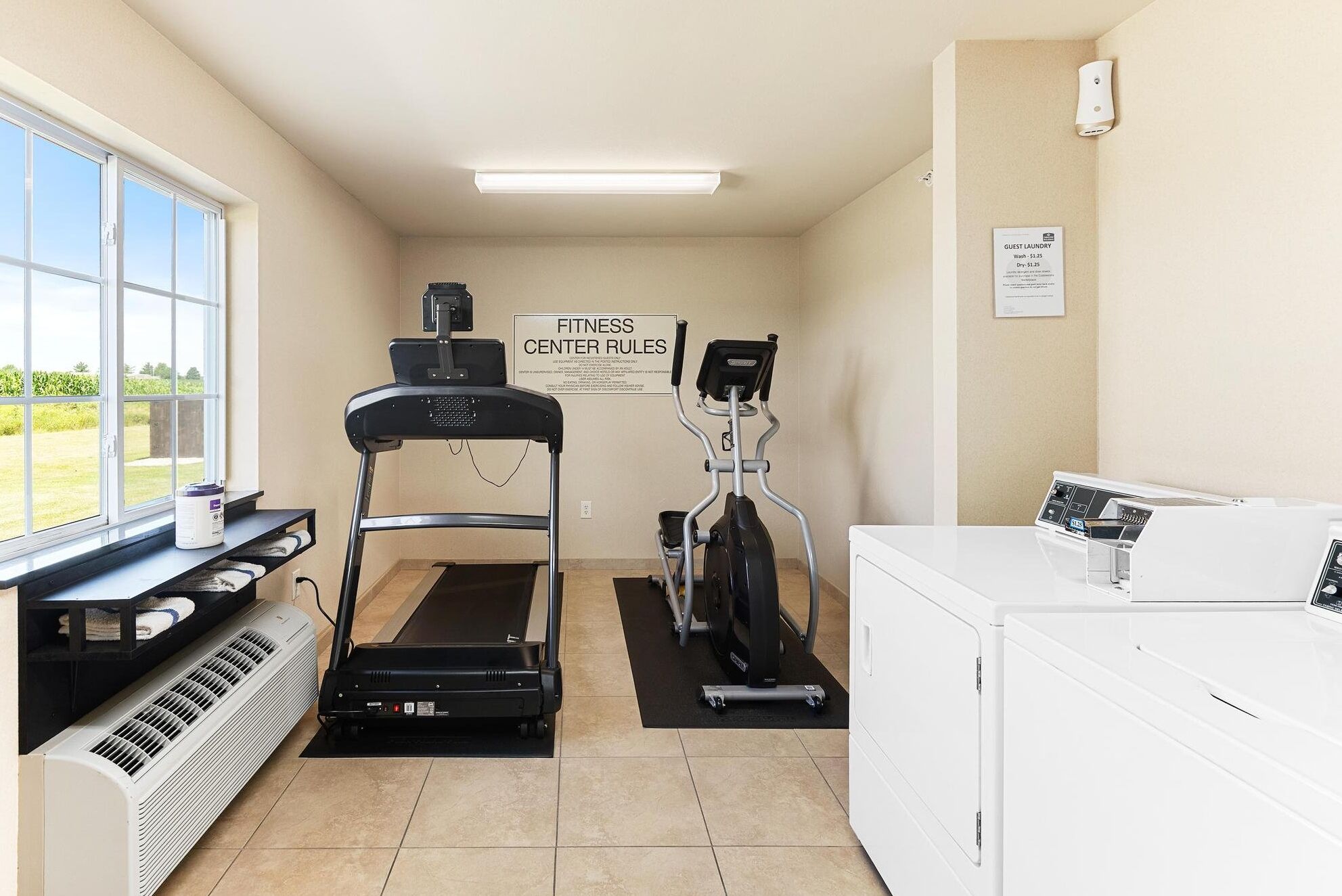 A fitness center with a treadmill, elliptical, and a washing machine.