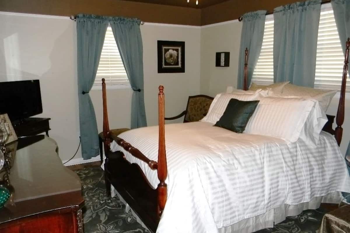 Un dormitorio con cama con dosel, un escritorio con silla y un televisor sobre un mueble.