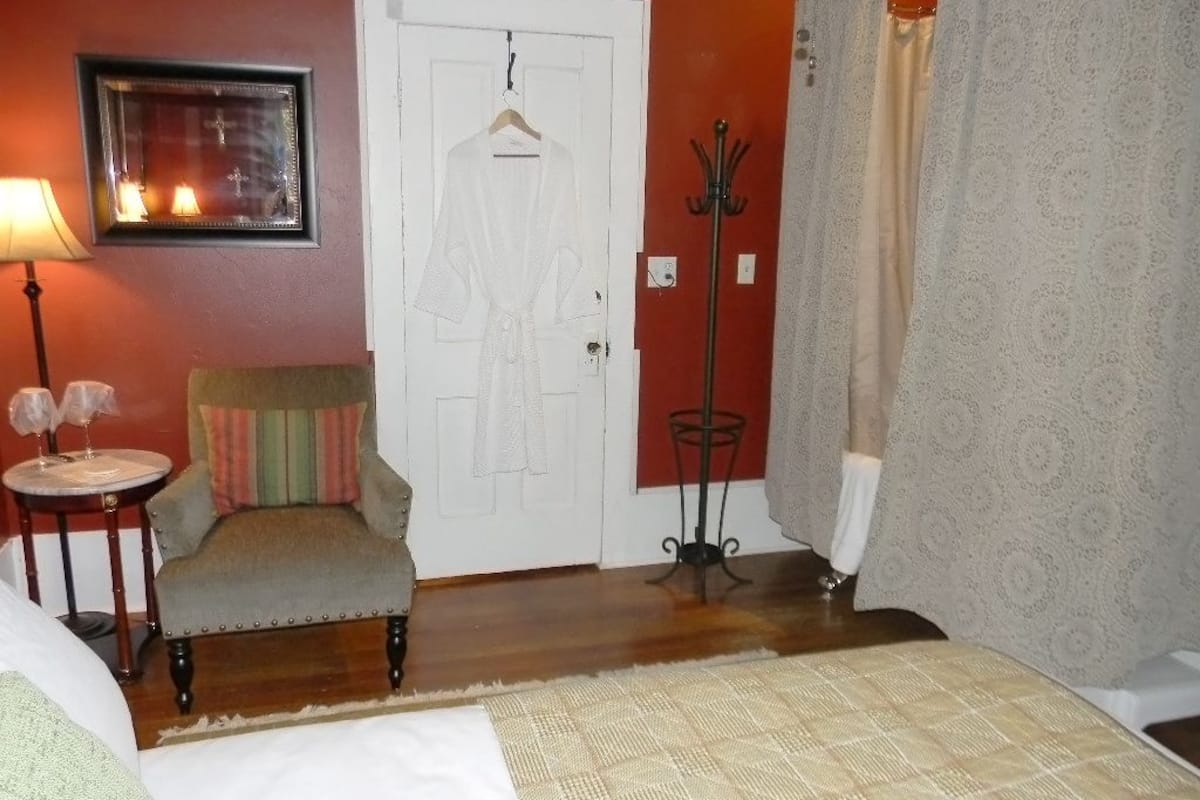 Un dormitorio con una cama, una silla, un perchero y una puerta.