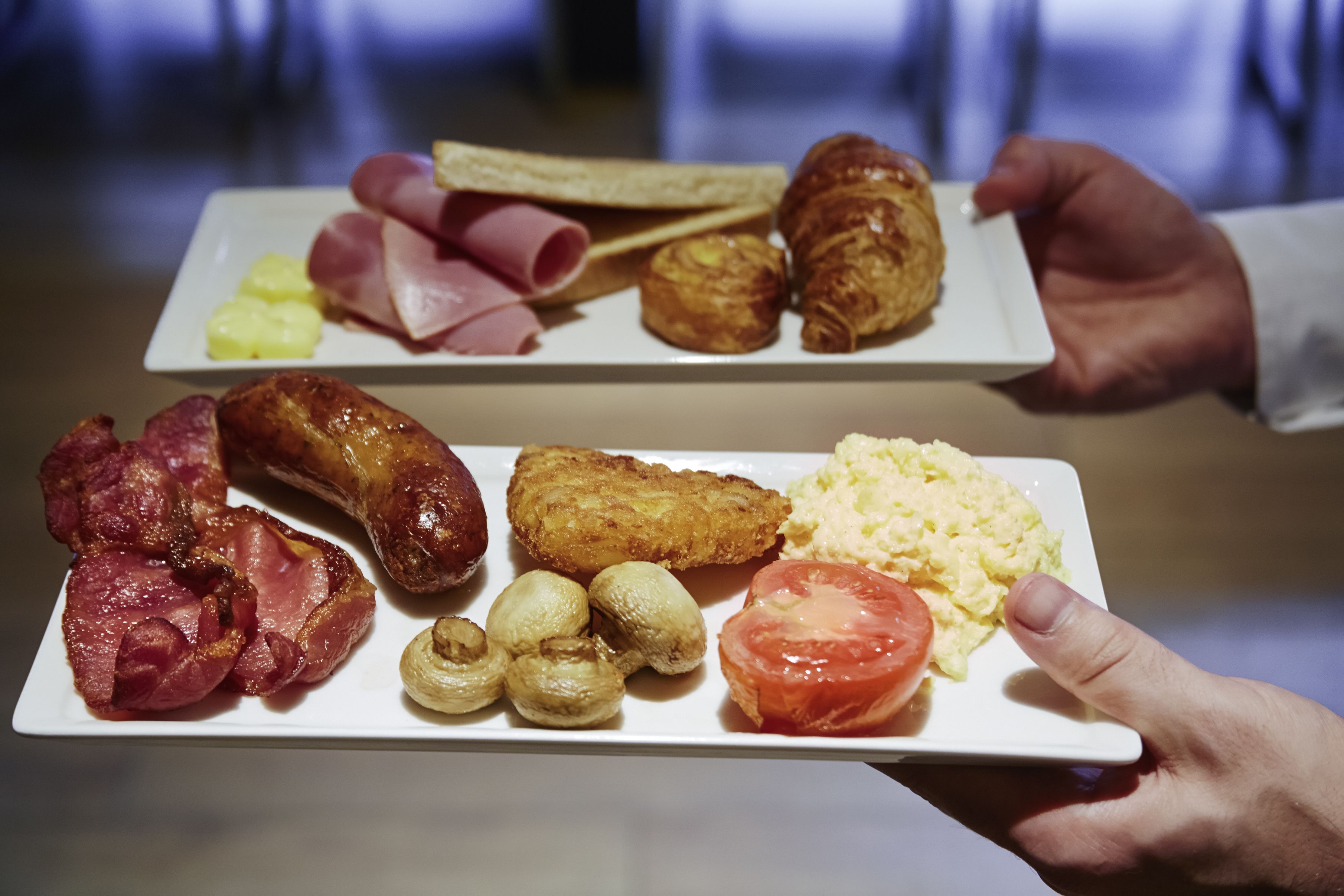 Ein Teller mit Schinken, Würstchen, Eiern und einem Croissant.
