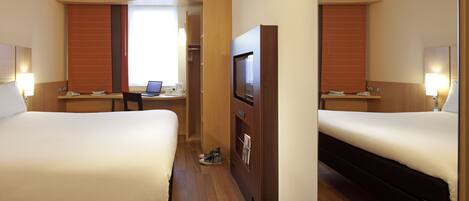 A hotel room with two beds, a desk with a laptop, a TV, and a shoe rack.
