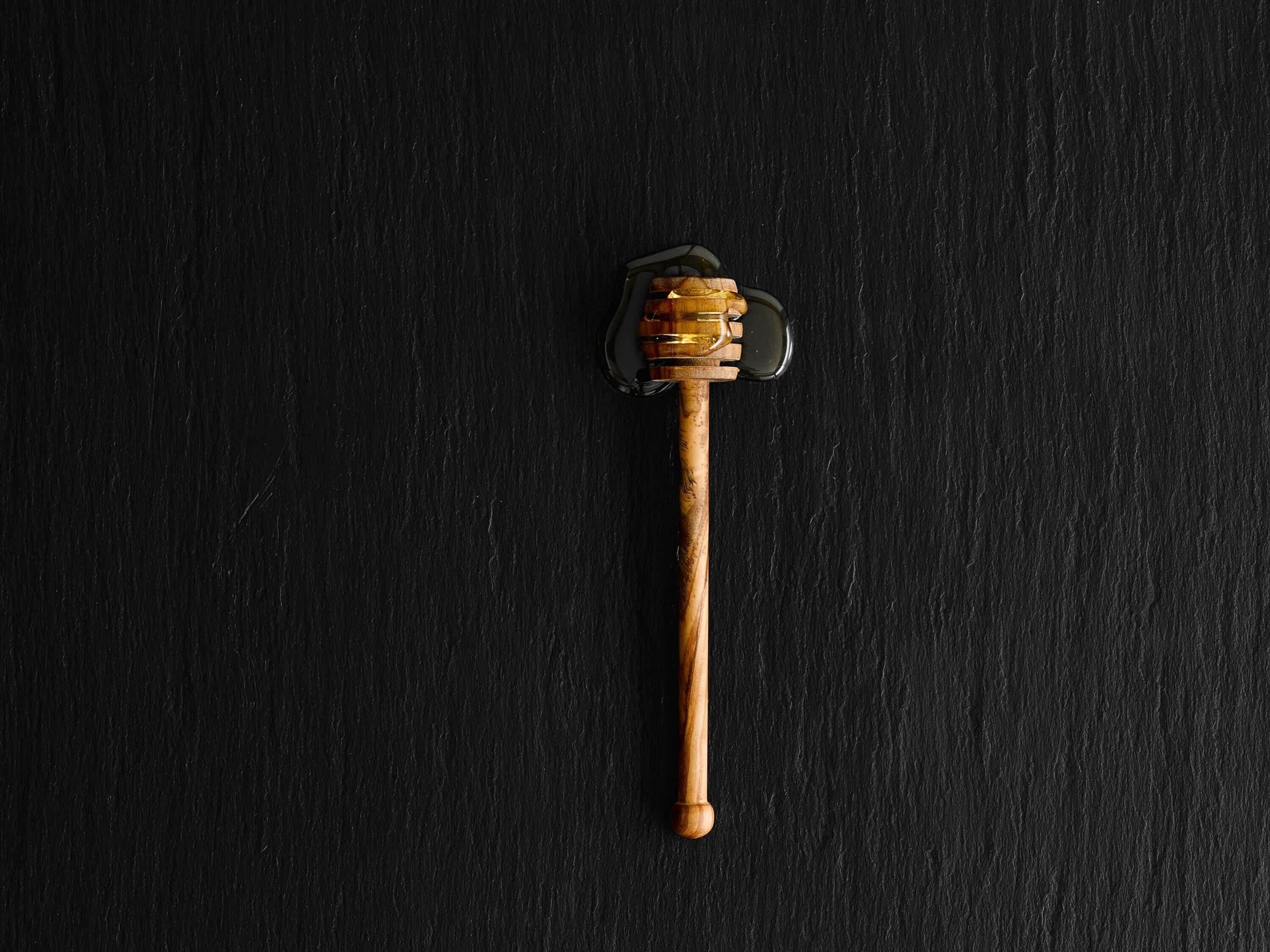 A honey dipper on a dark surface.