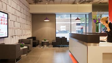 Welcome to our reception area, featuring a digital screen, comfortable seating, and a book collection.