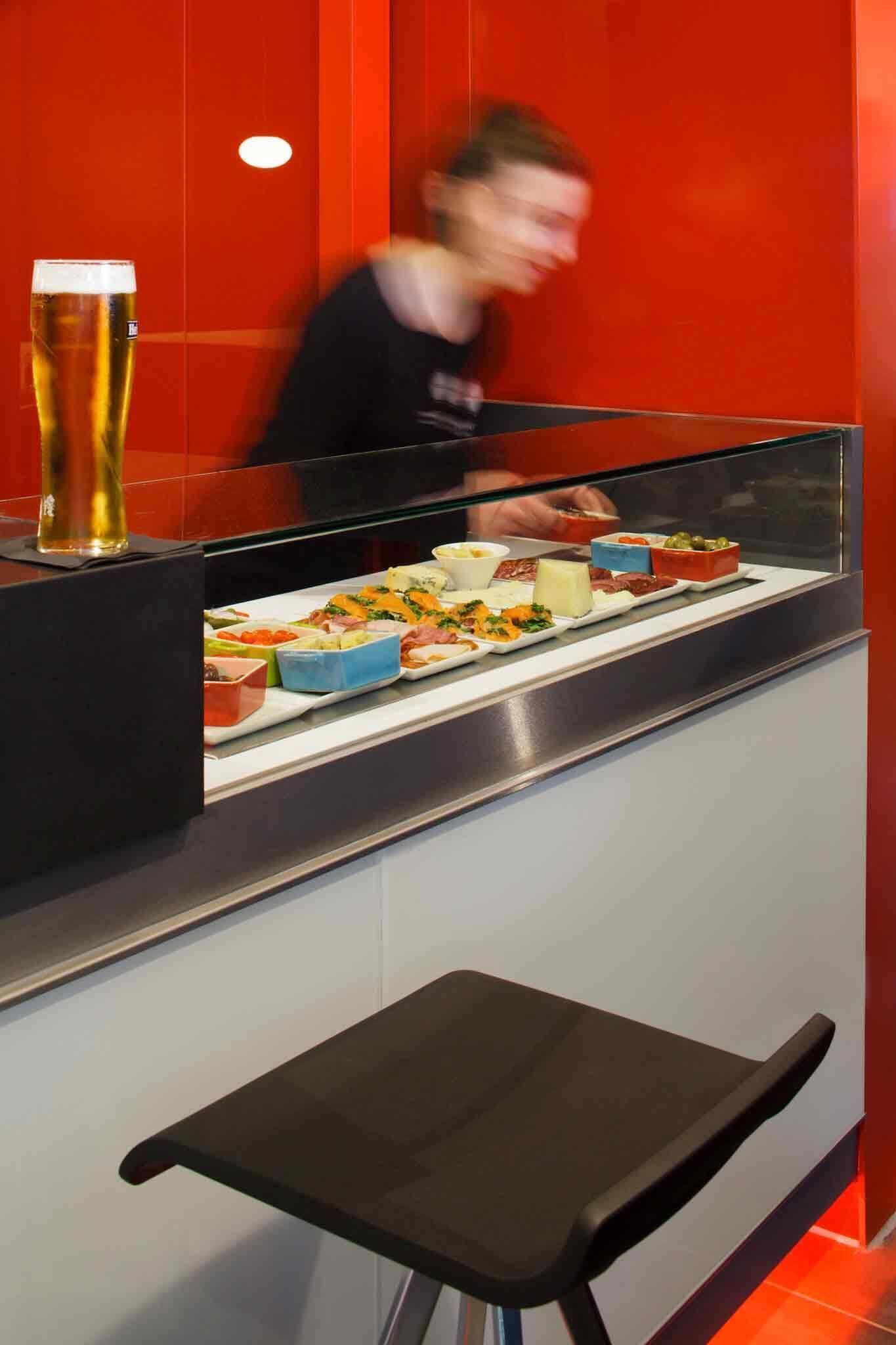 A buffet counter with various food items and a glass of beer.