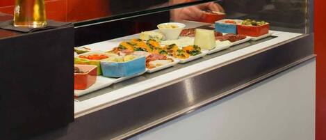A buffet counter with various food items and a glass of beer.