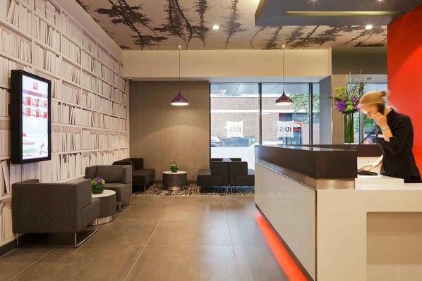 Un área de recepción moderna con estantería, asientos y mostrador.