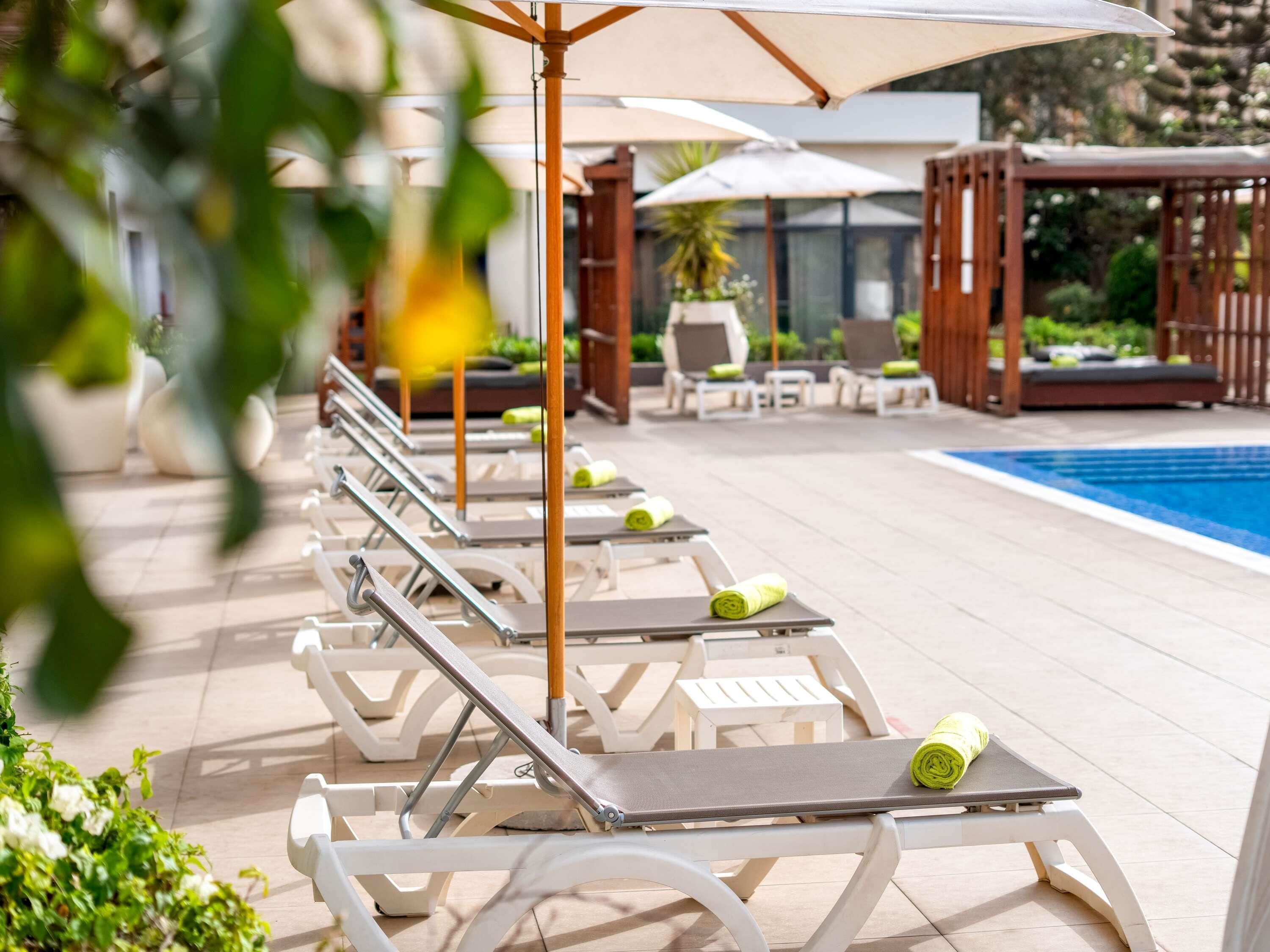 A poolside area with sun loungers and umbrellas.